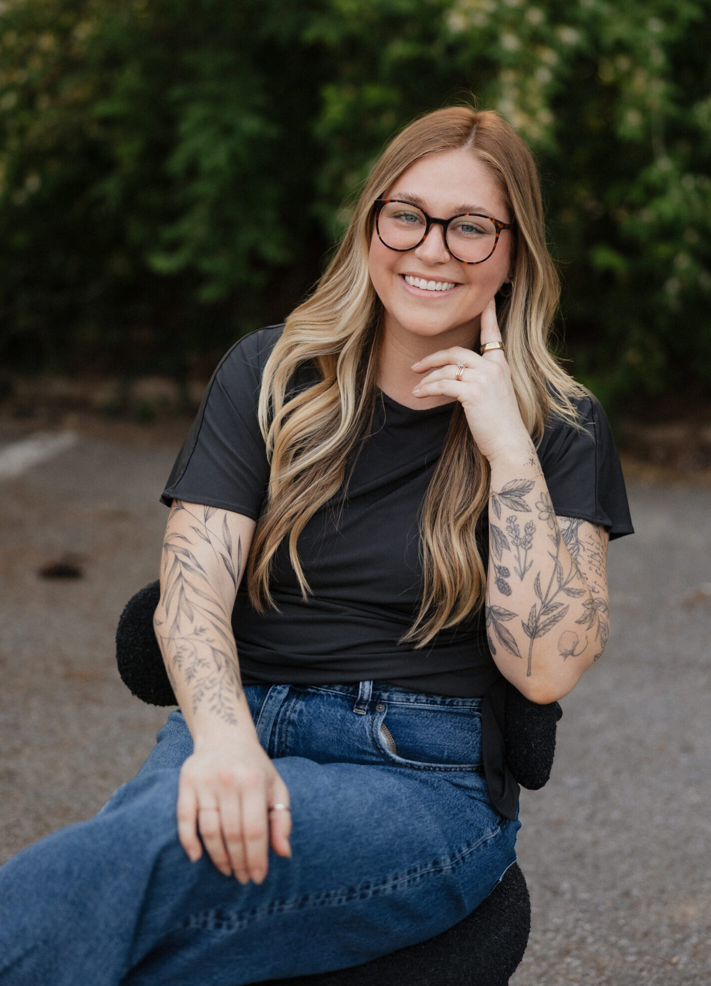 center for authentic growth Cadey Phipps, LMFT, therapist in Nashville, Tennessee, seated outdoors and smiling, with a green natural background.