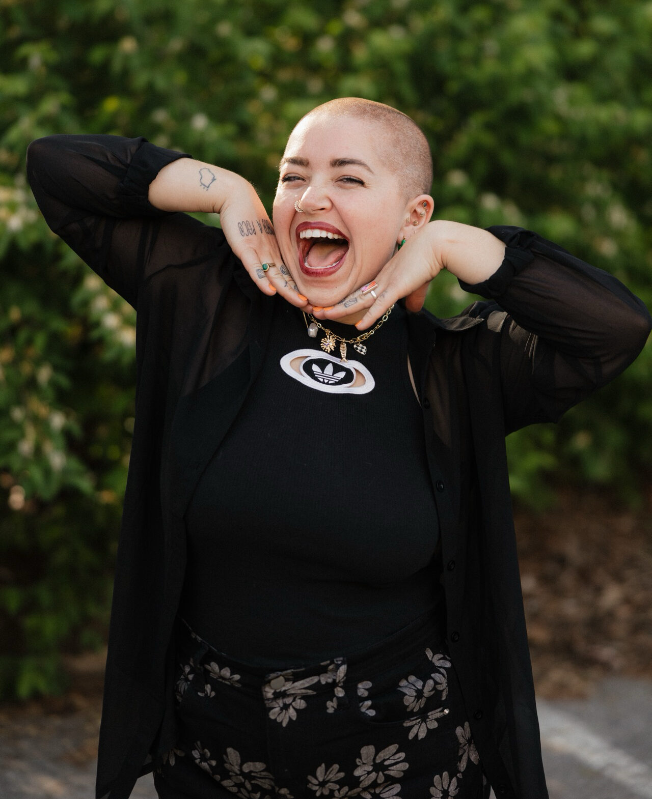payton-lindner-mmft-therapist-nashville-tn Payton Lindner, MMFT, therapist in Nashville, Tennessee, smiling outdoors with hands under their chin and greenery in the background.