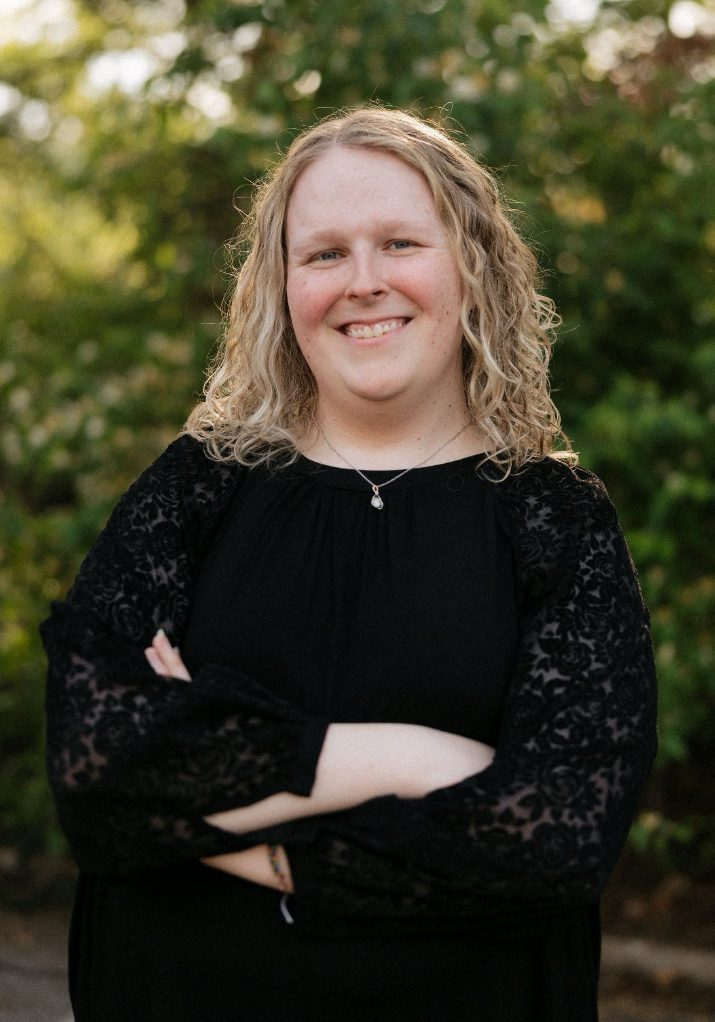 abbi-goins-ms-cmhc-nashville-therapist Abbi Goins, MS-CMHC, therapist in Nashville, Tennessee, smiling outdoors with arms crossed in front of a green, natural background.