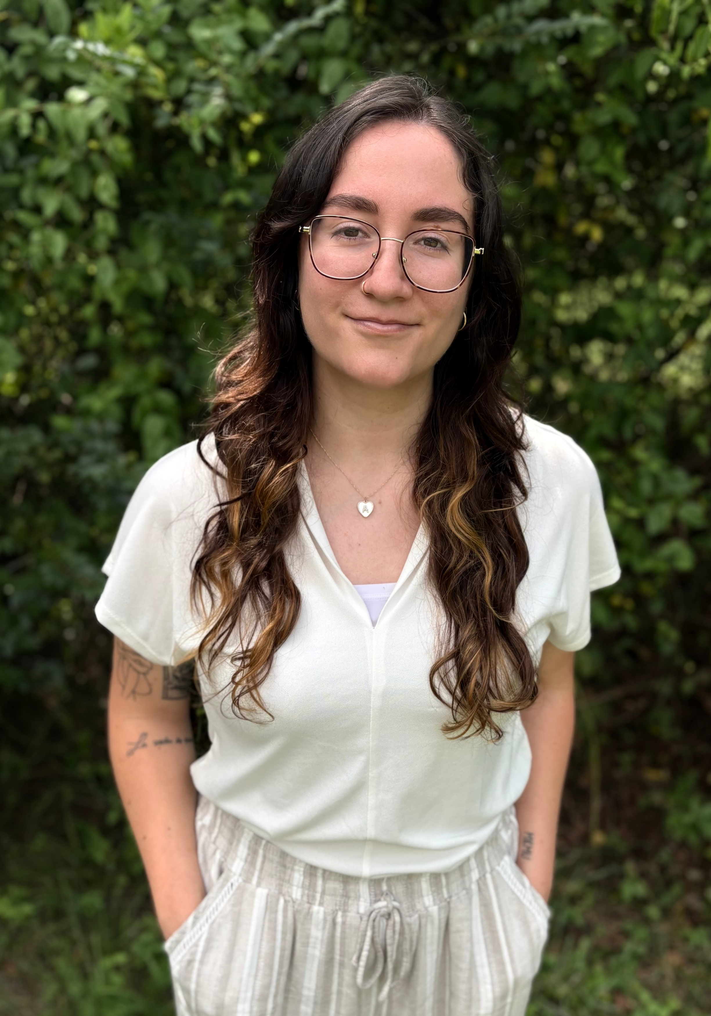 ana-quirk-lmft-nashville-therapist Cadey Phipps, LMFT, therapist in Nashville, Tennessee, seated outdoors and smiling, with a green natural background.
