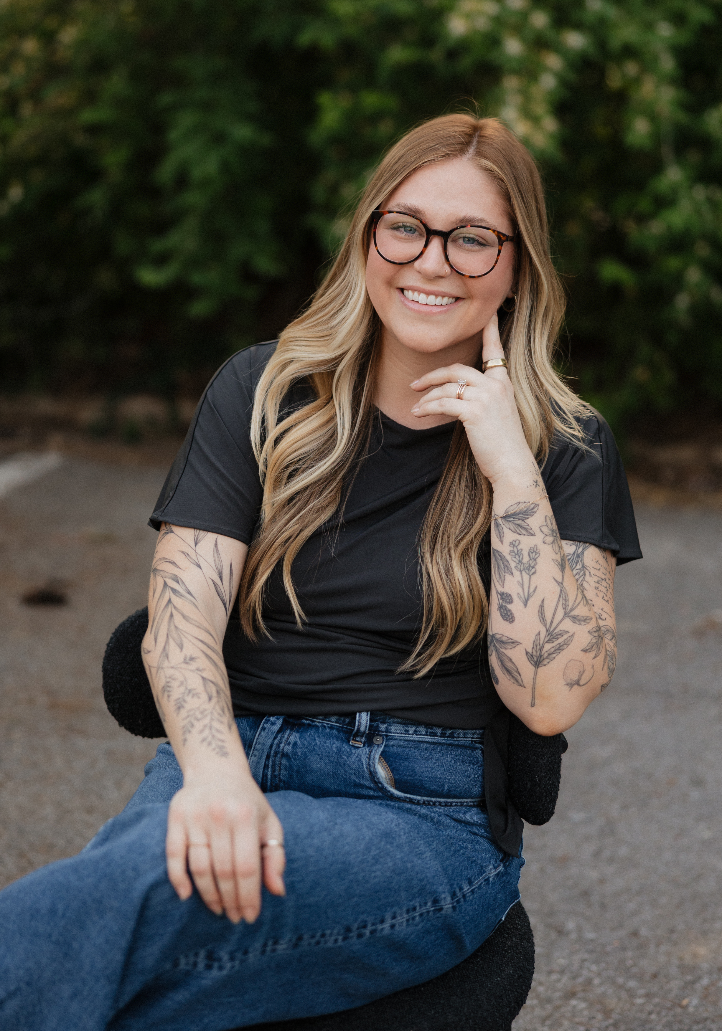 cadey-phipps-lmft-nashville-therapist Cadey Phipps, LMFT, therapist in Nashville, Tennessee, seated outdoors and smiling, with a green natural background.