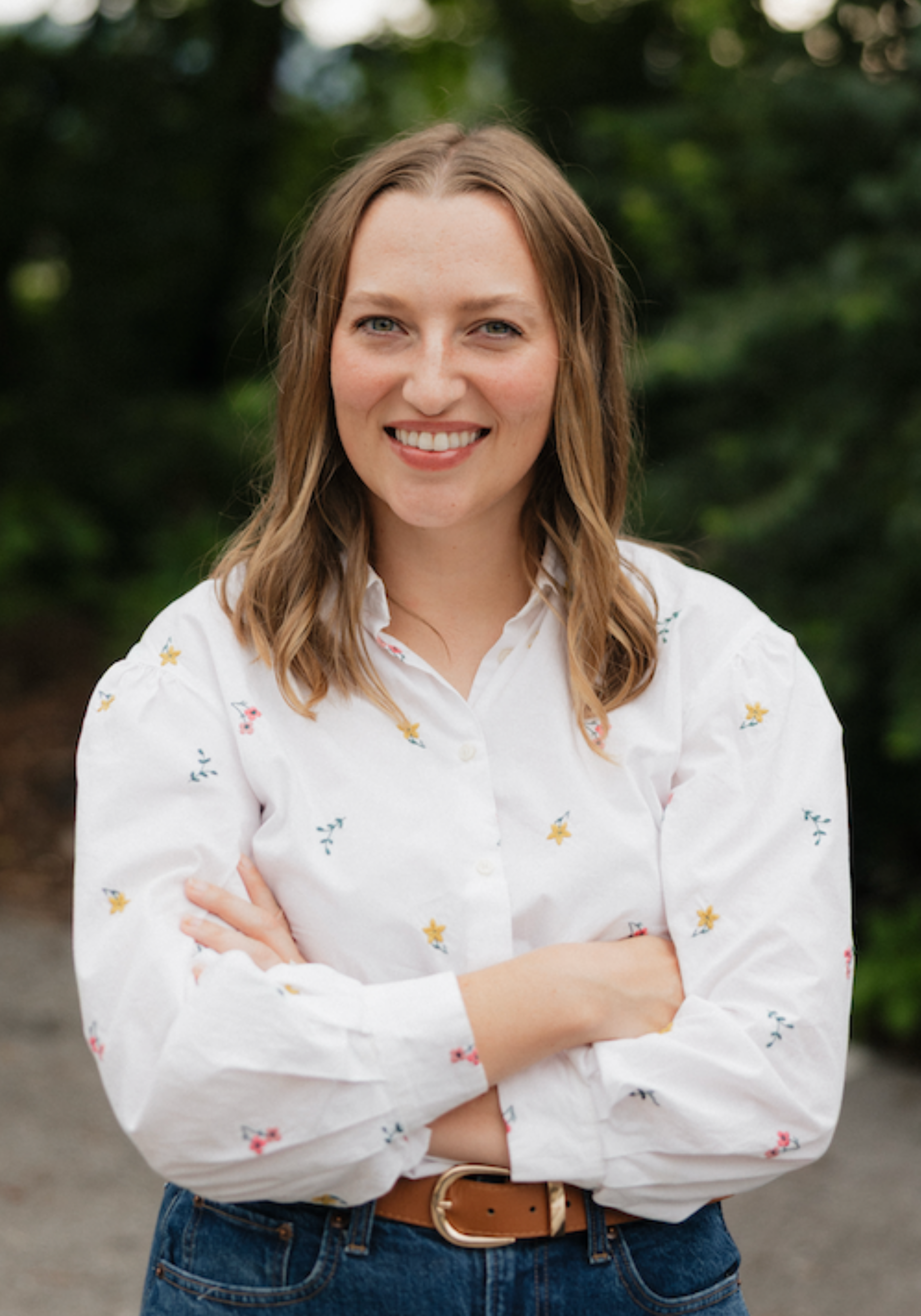Cadey Phipps, LMFT, therapist in Nashville, Tennessee, seated outdoors and smiling, with a green natural background.