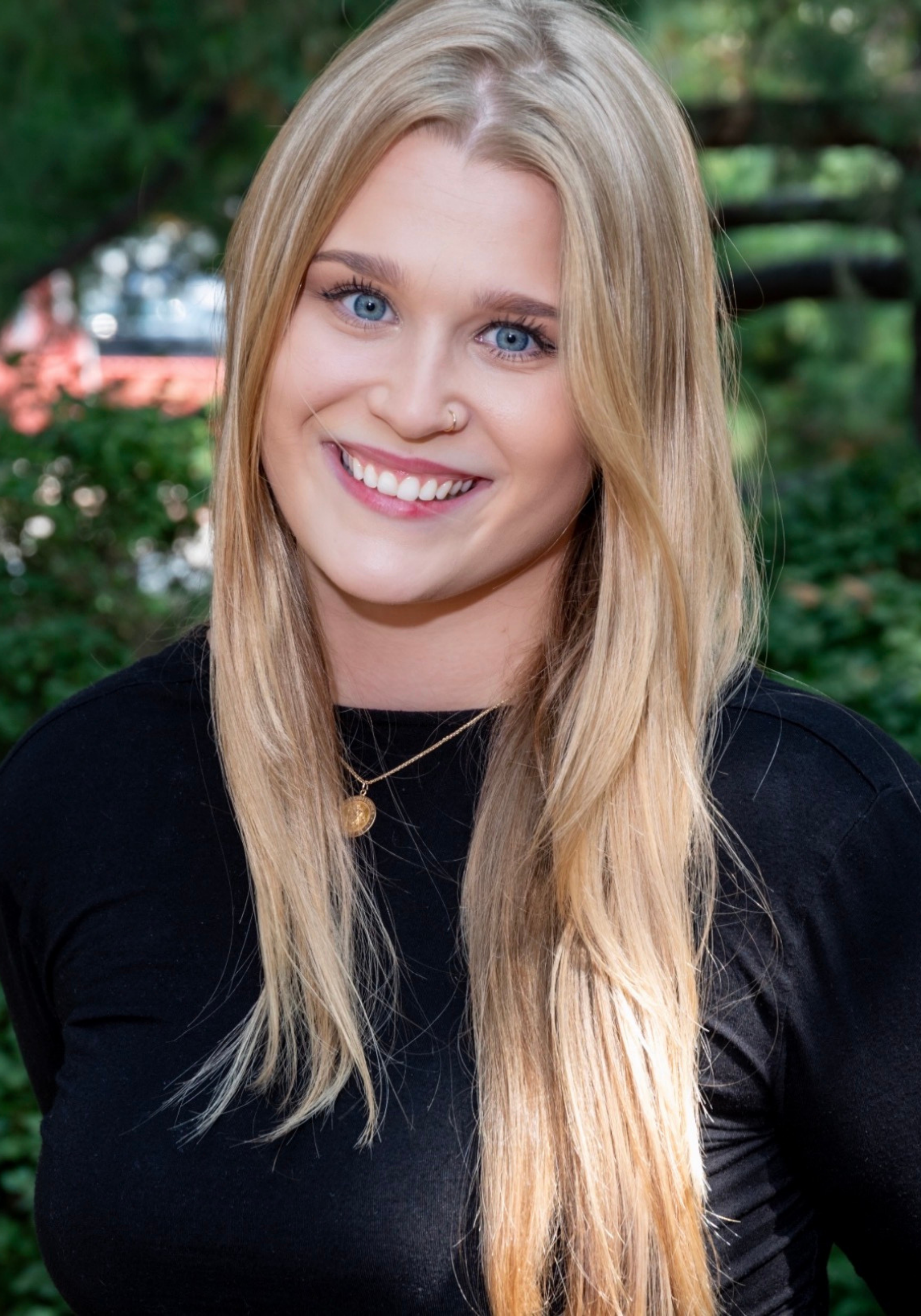 lauren-fisher-amft-nashville-therapist Cadey Phipps, LMFT, therapist in Nashville, Tennessee, seated outdoors and smiling, with a green natural background.
