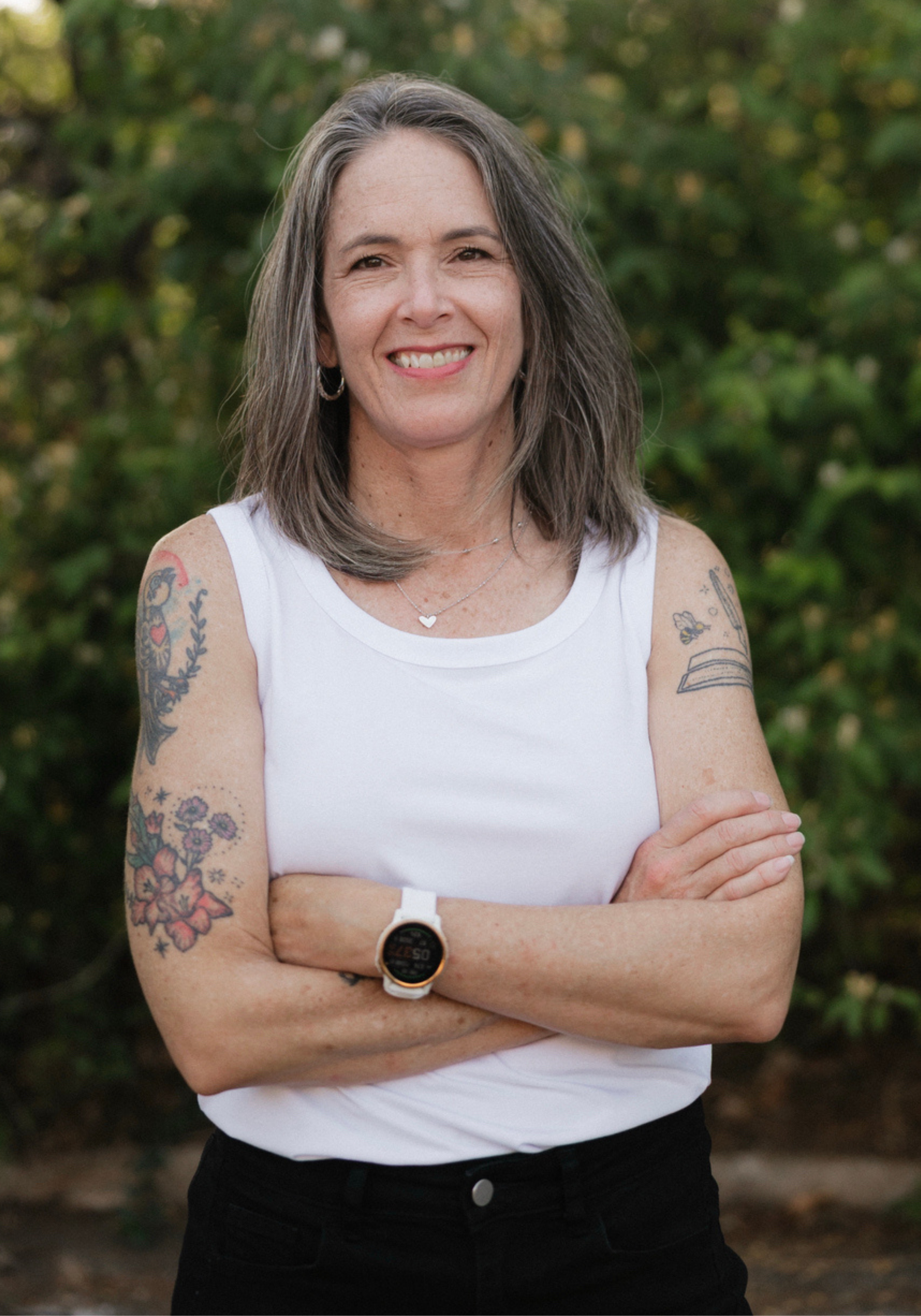 shelby-logsdon-lmft-nashville-therapist Shelby Logsdon, LMFT, therapist in Nashville, Tennessee, standing outdoors with arms crossed and a green natural background.
